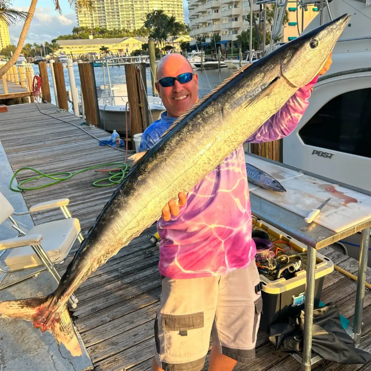 A family on the back deck holding a kingfish caught off Pompano Beach