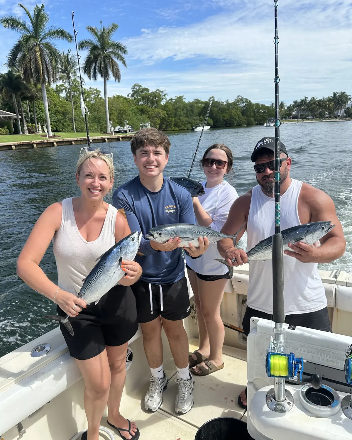 Four anglers on the back deck holding blackfin tuna caught off Pompano Beach